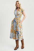 Woman wearing a floral dress with brown boots on a white background